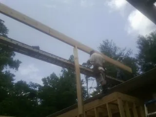 Carpenter setting a ridge beam over a new addition frame — Ice Dam Removal by Roofing Brothers in Wilburton