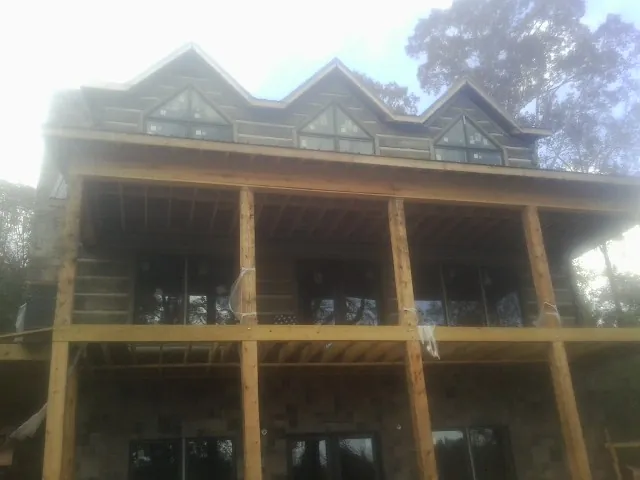 Dormers and porch framing on a large log home under construction — Roof Coating work by our crew in Wilburton