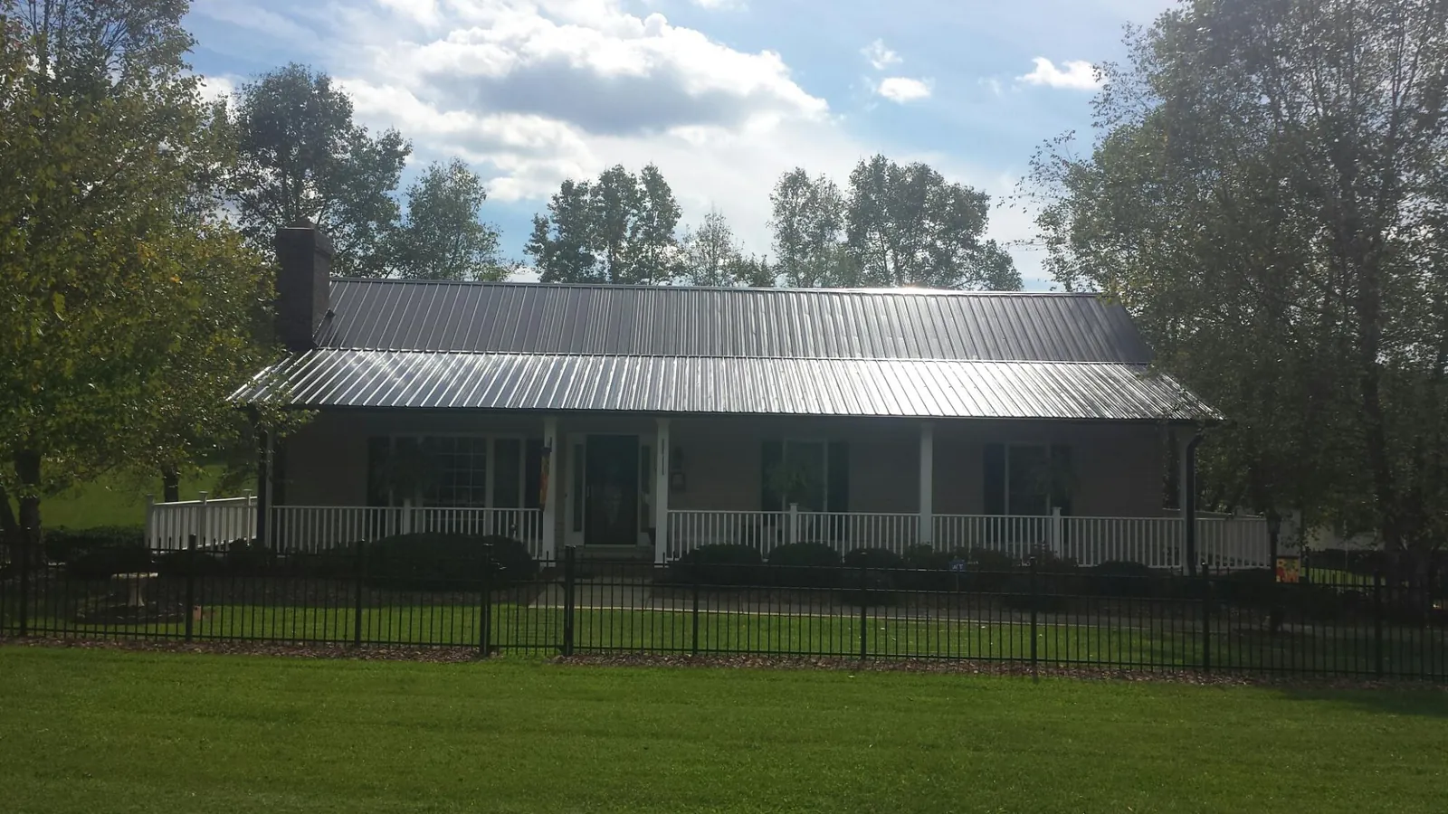 Gray metal roof on a brick ranch with a full width front porch — Gutter Guard Installation work by our crew in Wilburton