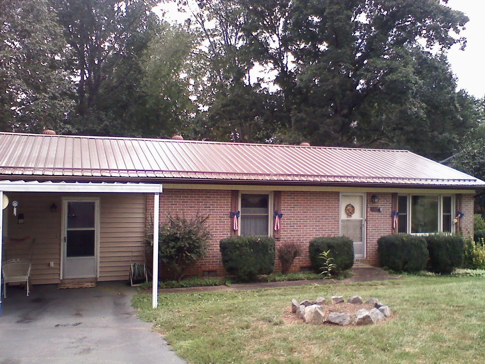 Bronze metal roof and carport on a brick ranch home — Roof Repair work by our crew in Wilburton